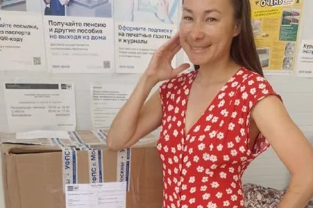 Женщина рядом с коробкой вещей по программе «Тепло наших сердец»